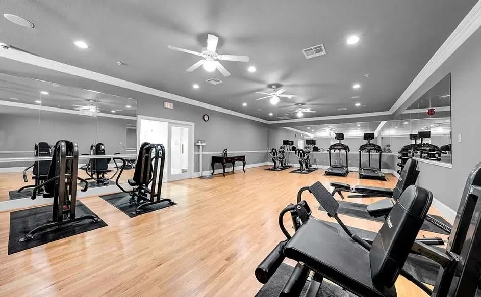 A modern gym with a variety of exercise equipment and wooden flooring.