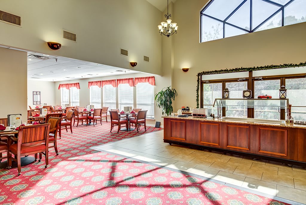 A spacious dining area with wooden furniture, large windows, and a chandelier.