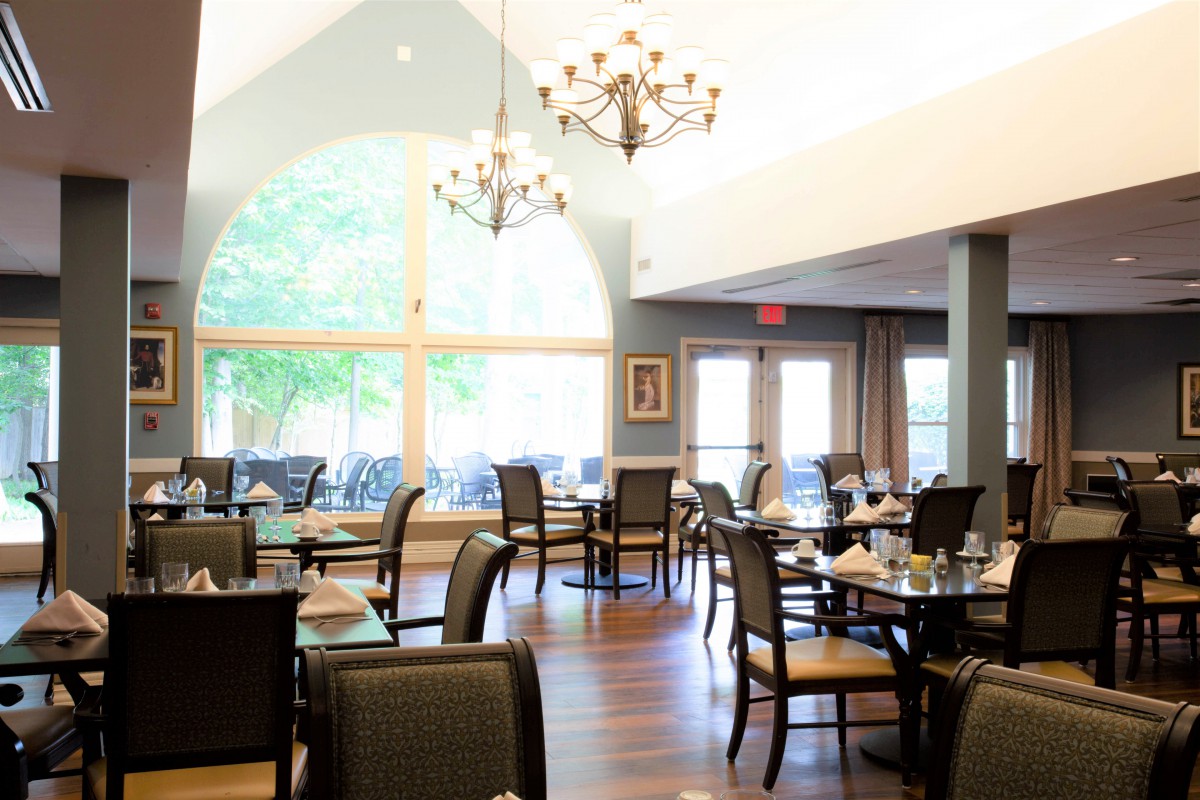 A well-lit restaurant dining area with elegant chandeliers and neatly arranged tables and chairs.