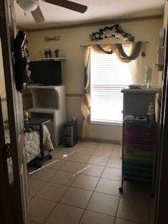 A small bedroom with a television and storage drawers, illuminated by natural light from a window.