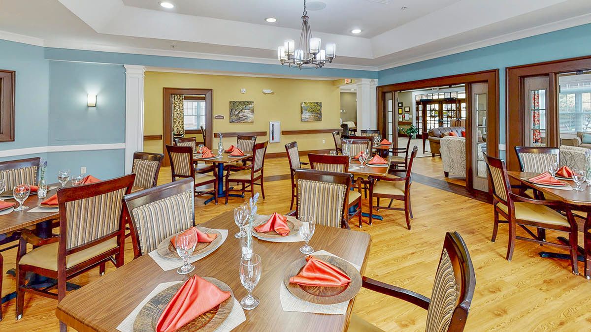 A neatly set dining area with tables and chairs, featuring red napkins and elegant decor.