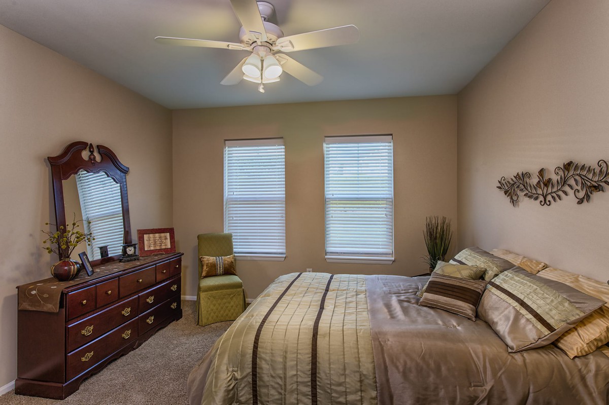 A cozy bedroom with a bed, dresser, and two windows.