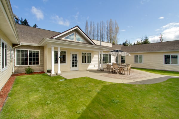 A spacious backyard with a patio and outdoor furniture, surrounded by manicured lawns.