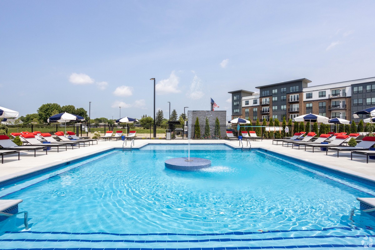 An outdoor swimming pool surrounded by apartment buildings on a sunny day.