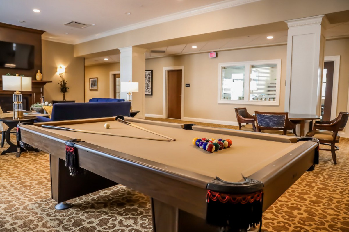 A modern game room featuring a pool table with billiard balls set up for play.