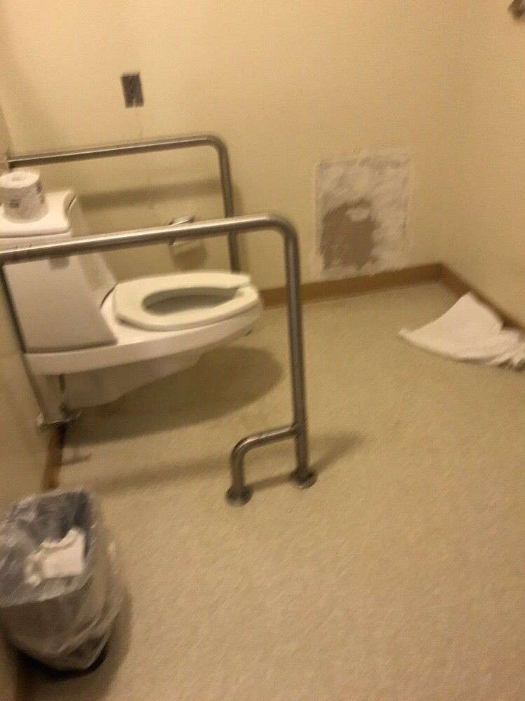 An accessible bathroom with handrails and a wall-mounted toilet.