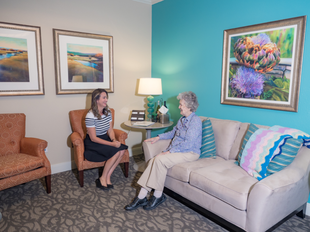 Two people sitting and conversing in a decorated living room.