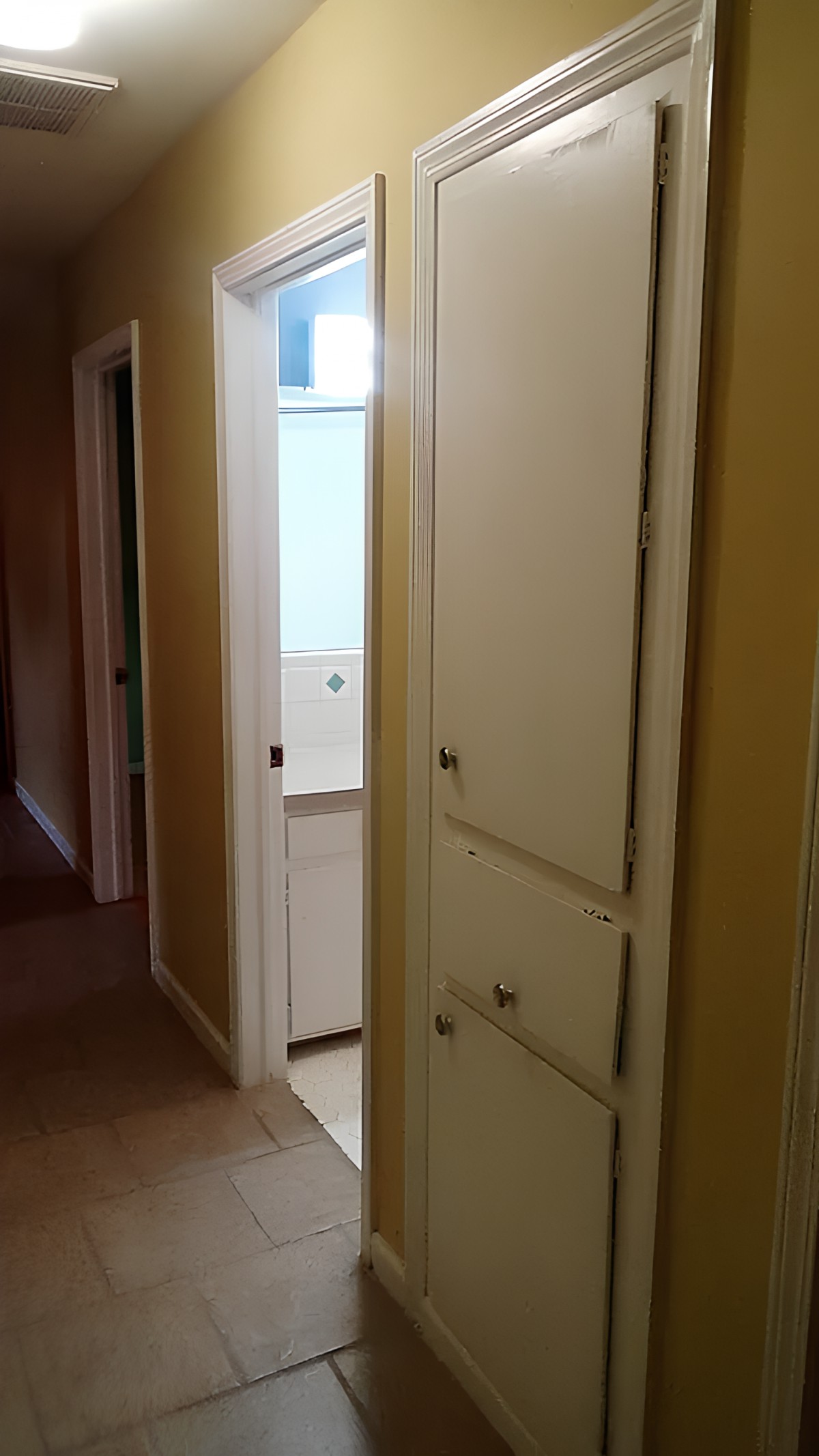 A hallway with a cabinet and partially open door leading to another room.