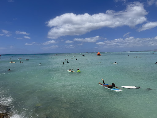 A vibrant day at the beach with surfers enjoying the clear waters under a bright blue sky.