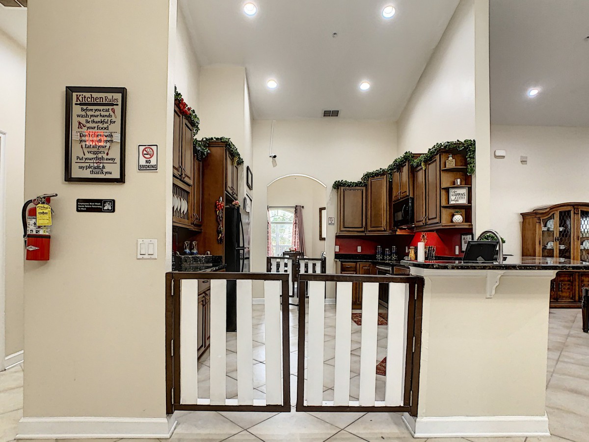 A modern kitchen with wooden cabinets and decorative elements, featuring a pet gate at the entrance.