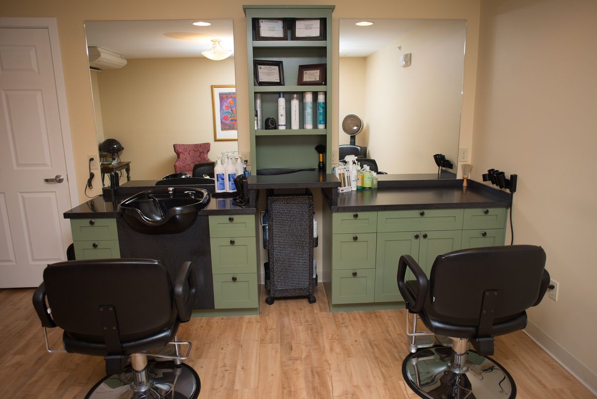 Cozy hair salon interior with styling chairs, sinks, and shelves stocked with hair products.