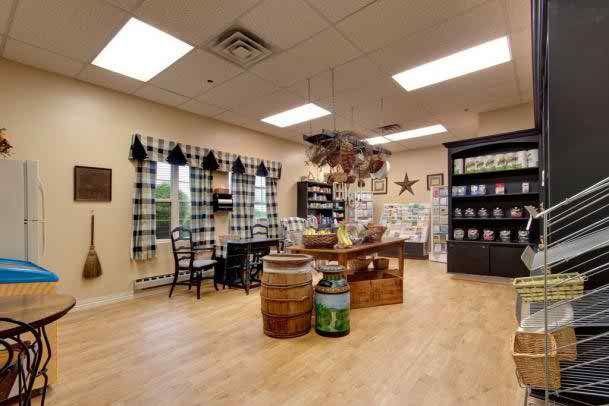 A cozy store interior featuring rustic country decor and wooden floors, with various items displayed on shelves and barrels.