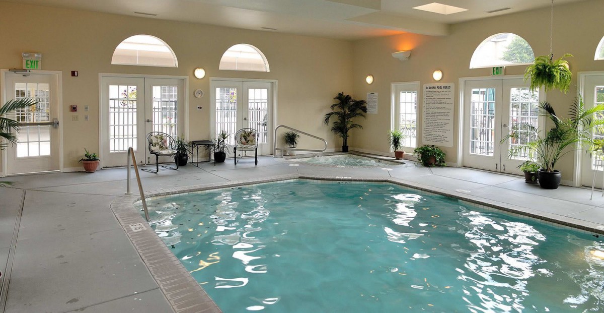 A serene indoor swimming pool area with elegant seating and ambient lighting.