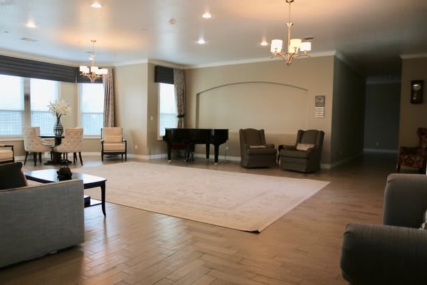 A spacious living room featuring a grand piano, ample seating, and elegant lighting.