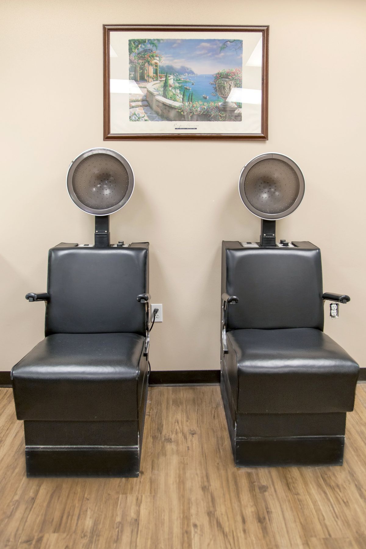 Two salon chairs with hair dryers in a well-lit room.
