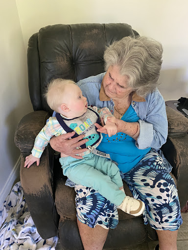 A heartwarming moment between a baby and an elderly woman, showcasing the bond of family.