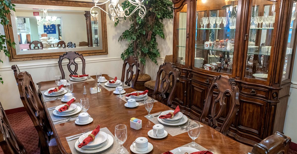 An elegantly set dining room table with matching chairs and a chandelier overhead.