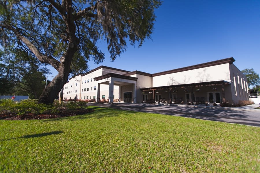 A modern building surrounded by green grass and trees under a clear blue sky.