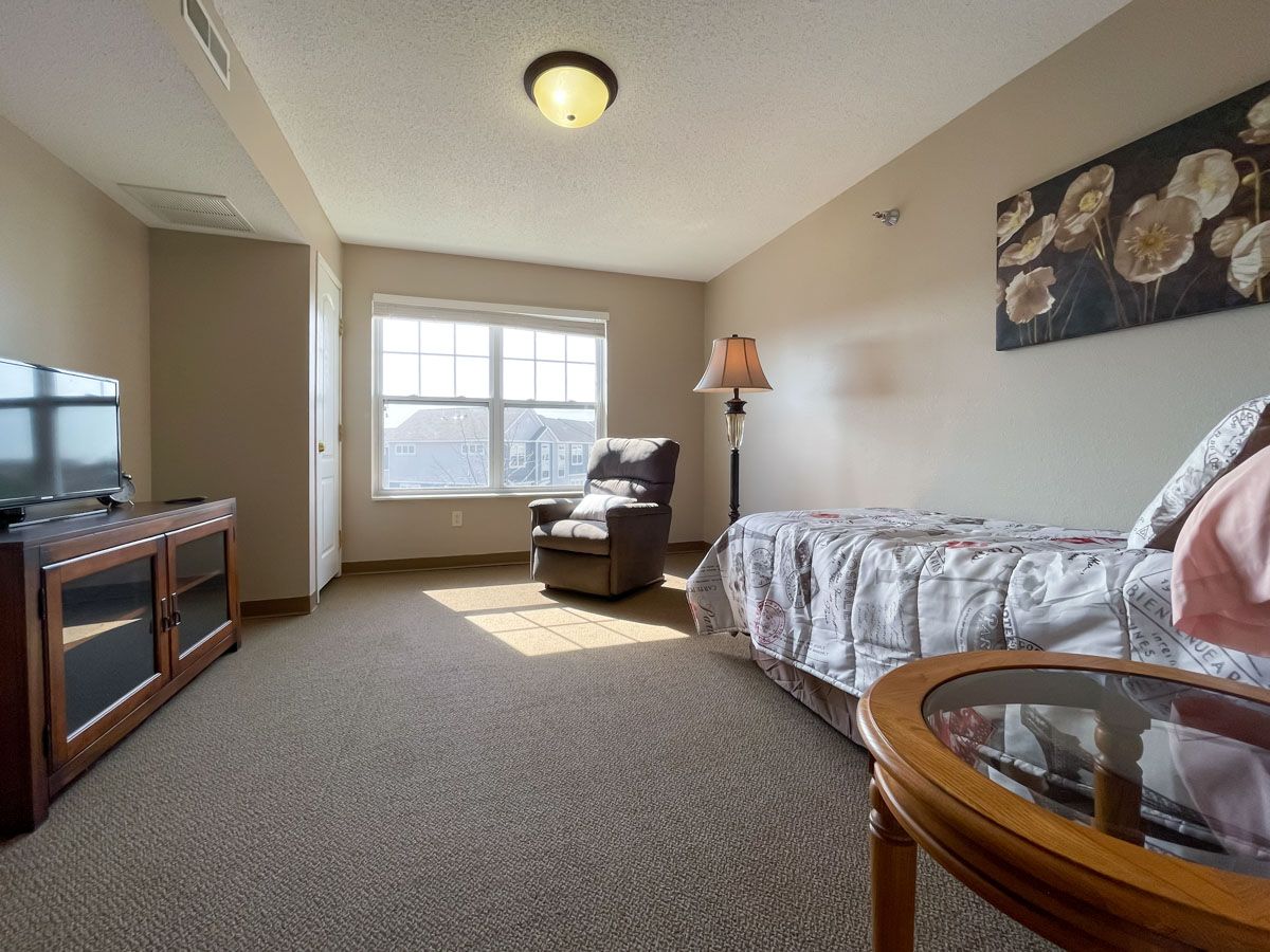 A cozy room with a bed, armchair, and window providing ample natural light.