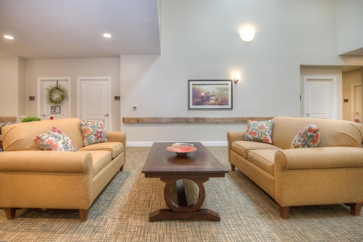 A cozy living room featuring two beige sofas facing each other with a wooden coffee table in between, decorated with a small bowl, under soft lighting.