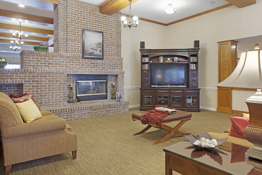 A cozy living room featuring a brick fireplace, television, and comfortable seating.