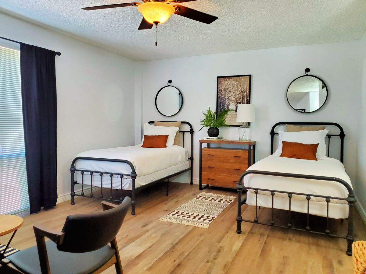 A modern bedroom with two twin beds and minimalist decor.