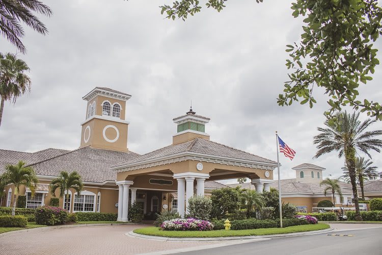 A well-maintained building with a grand entrance and landscaped surroundings under a cloudy sky.