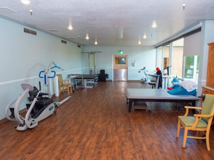 A rehabilitation room equipped with exercise machines and therapy tables.