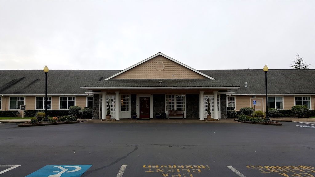 A building entrance with a parking lot featuring handicap parking spaces.