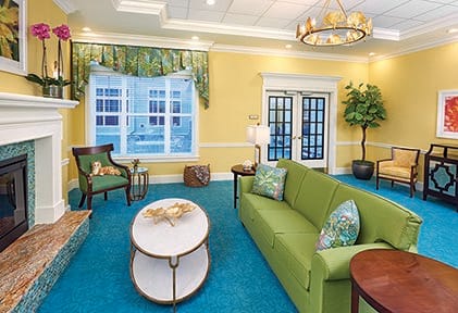 A brightly decorated living room with a green sofa and blue carpet.