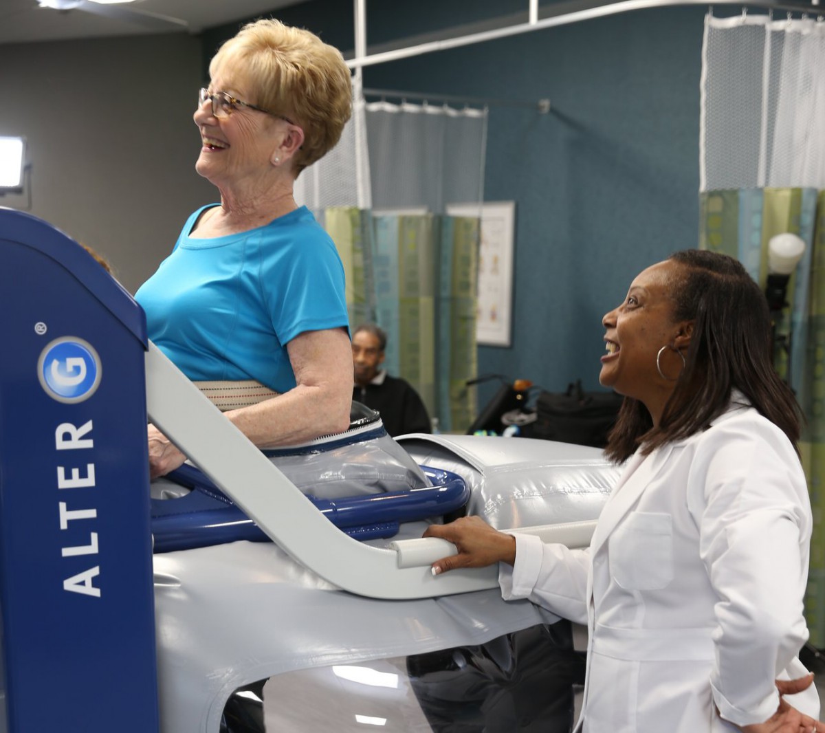 A physical therapist assists a woman using specialized rehabilitation equipment.