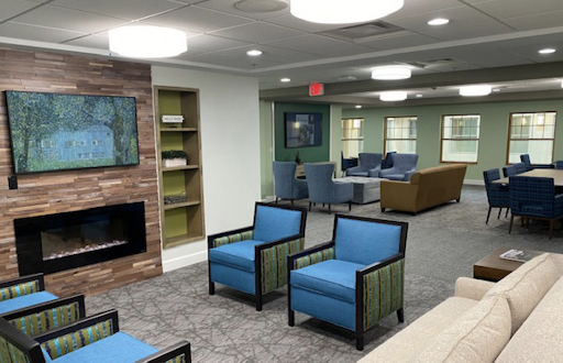 A modern lobby featuring comfortable blue chairs, a cozy fireplace, and a welcoming atmosphere.