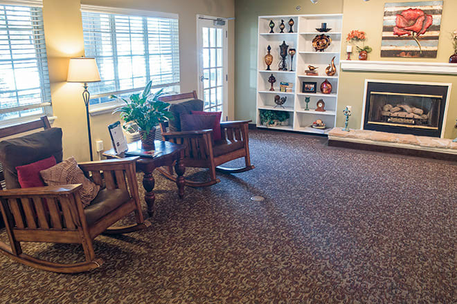 A cozy living room with comfortable seating, decorative shelves, and a fireplace.