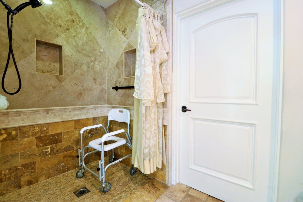 A luxurious bathroom featuring a shower chair and robe hanging near a marble wall.