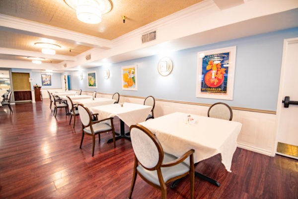 A well-lit restaurant dining area with neatly arranged tables and chairs, adorned with framed artwork on the blue walls.