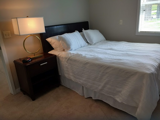 A cozy bedroom setup featuring a neatly made bed and a stylish nightstand with a lamp.