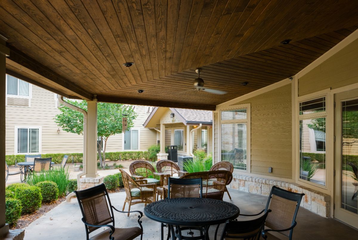A cozy outdoor patio with comfortable seating and a ceiling fan.