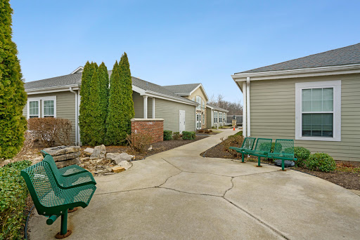 A peaceful residential pathway surrounded by greenery and benches.