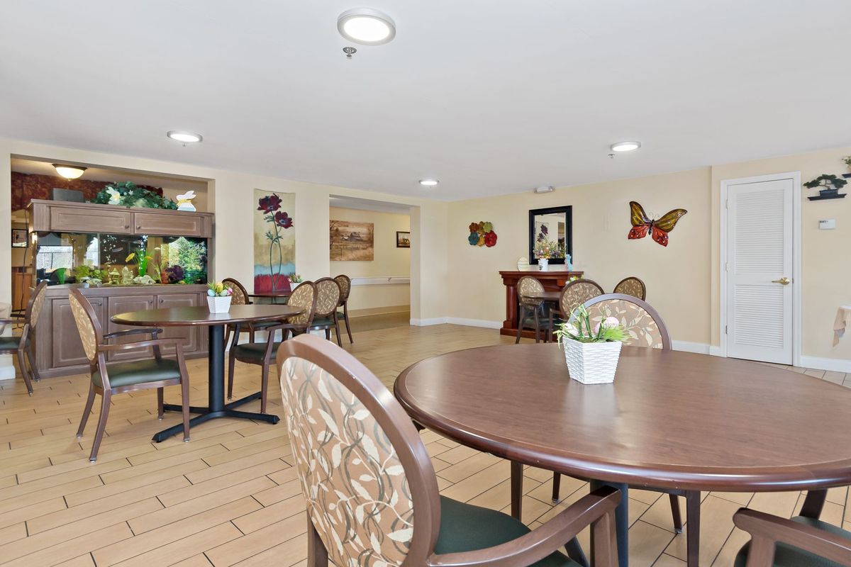 A cozy dining room with round tables, chairs, and decorative wall art.