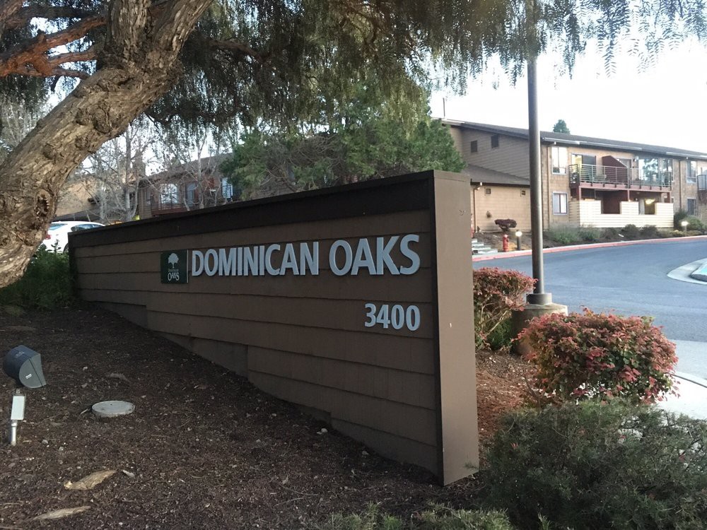 A sign for Dominican Oaks located in an outdoor setting.