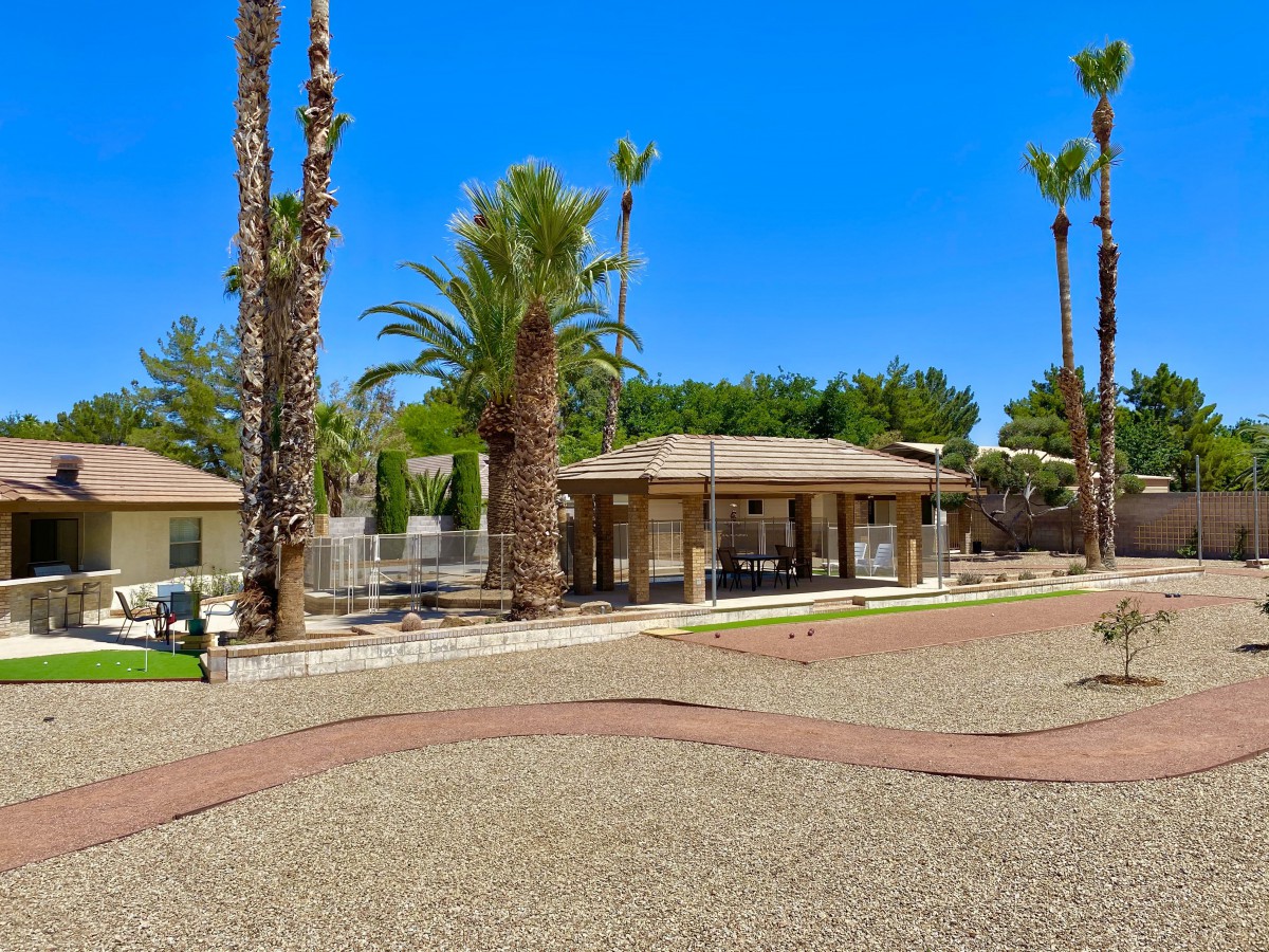 A sunny day at a house surrounded by palm trees and an open yard.