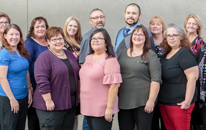 A group of adults standing together, smiling for the photo.