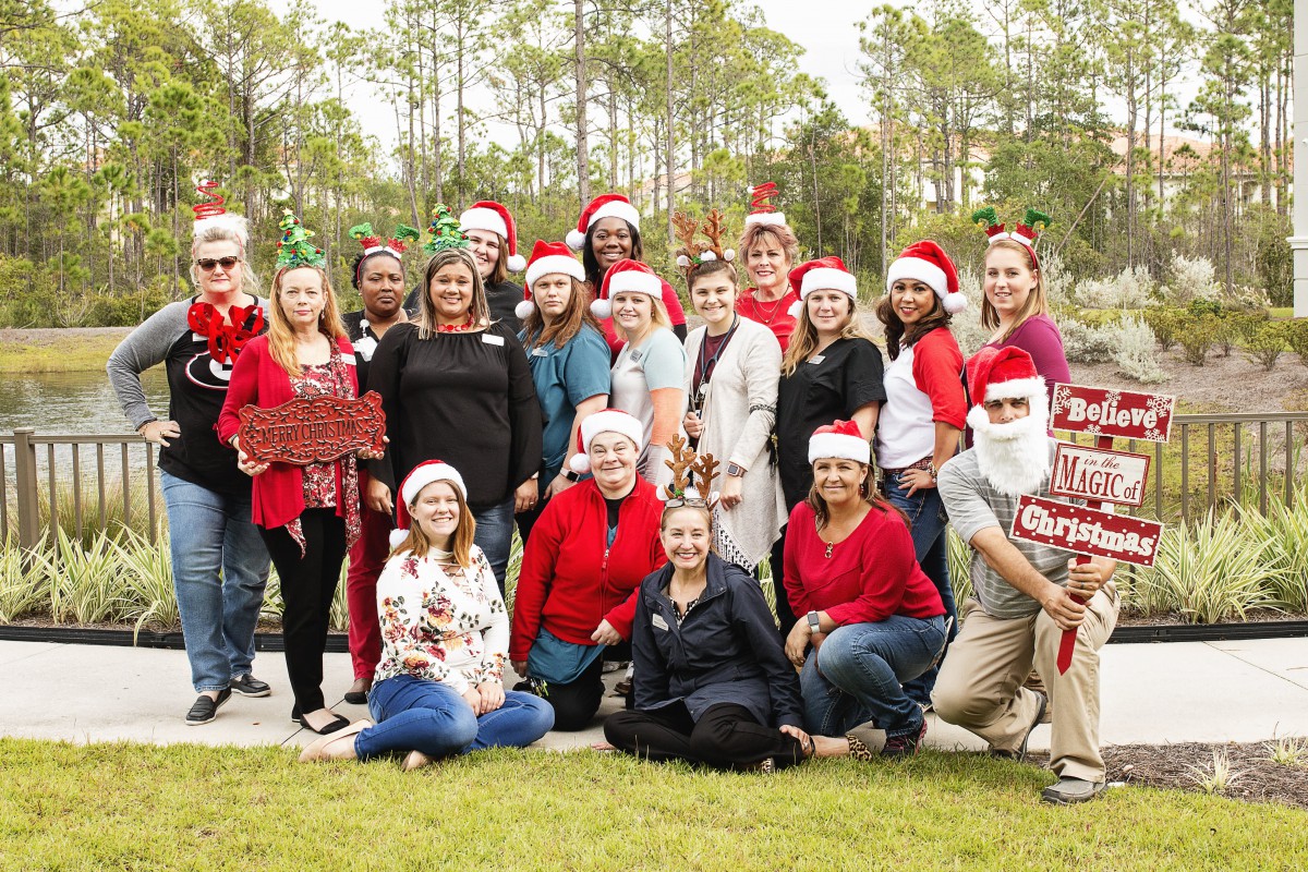 A group of people wearing Santa hats posing together outdoors in a festive holiday setting.