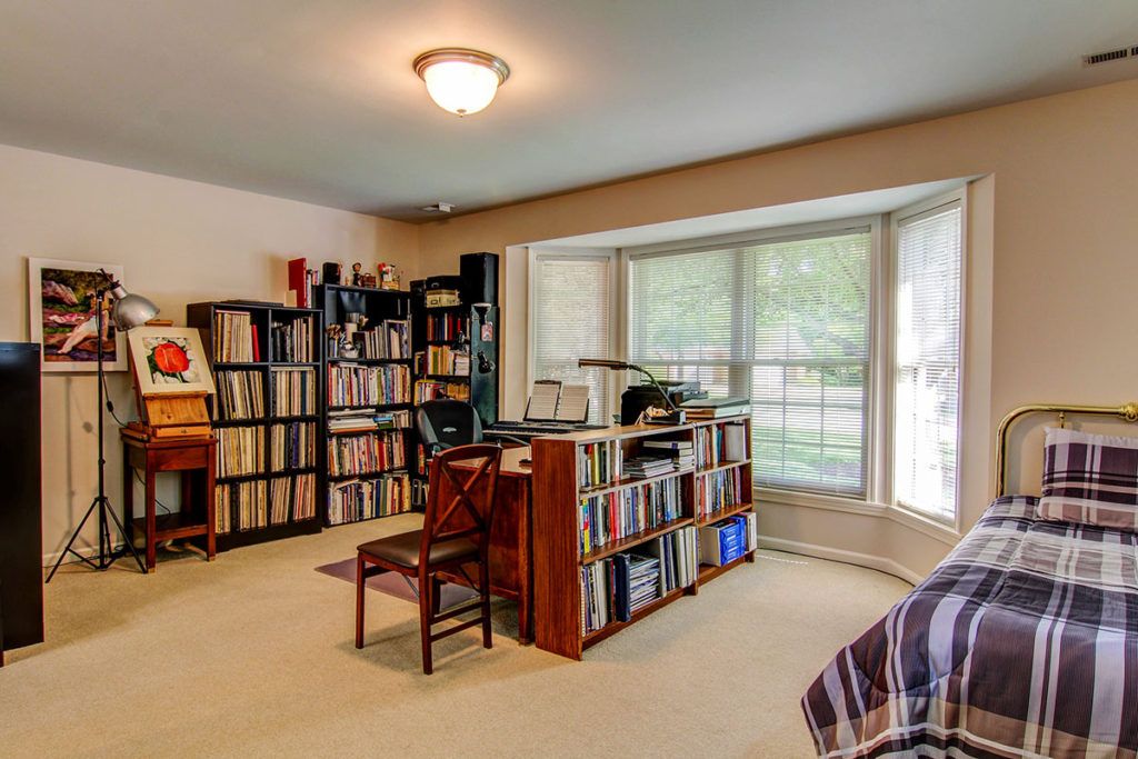 A cozy home office with bookshelves, a desk, and a large window.