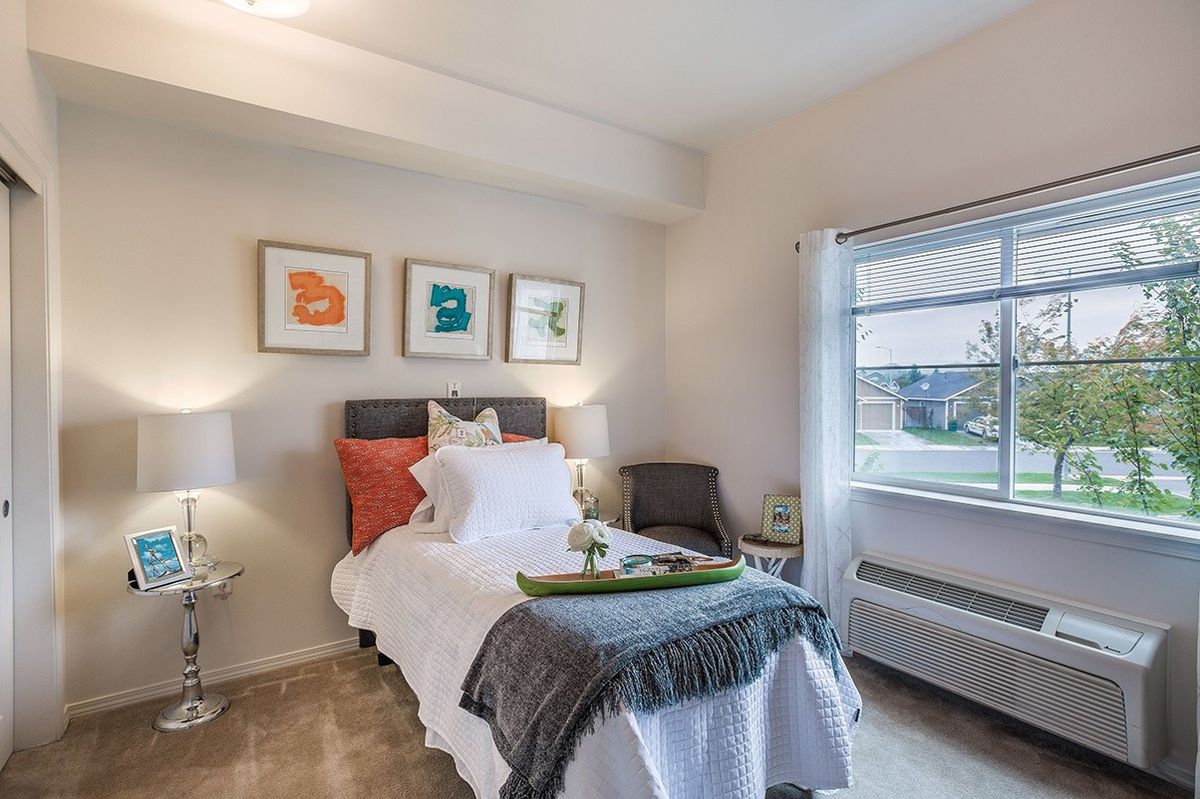 A modern and cozy bedroom with minimalist decor, featuring a comfortable bed, artwork on the wall, and natural light from the window.