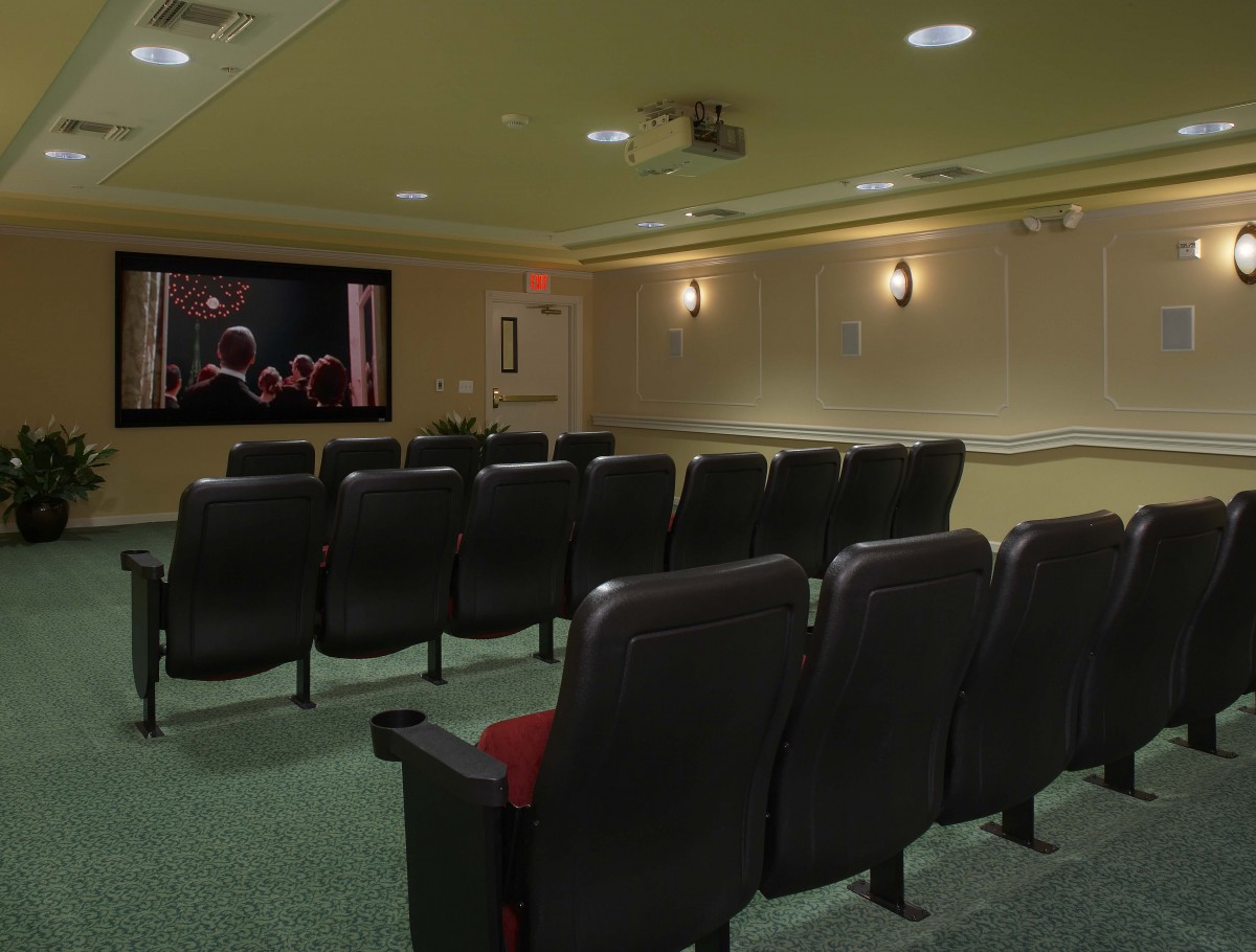 A cozy home theater setup with rows of comfortable seating facing a large screen.