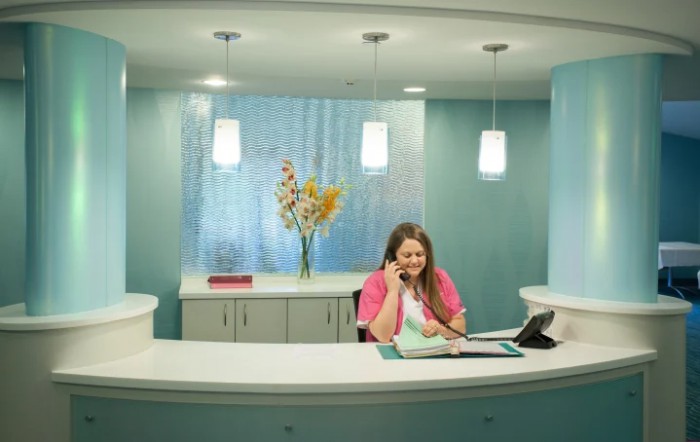 A woman at a reception desk talking on the phone.