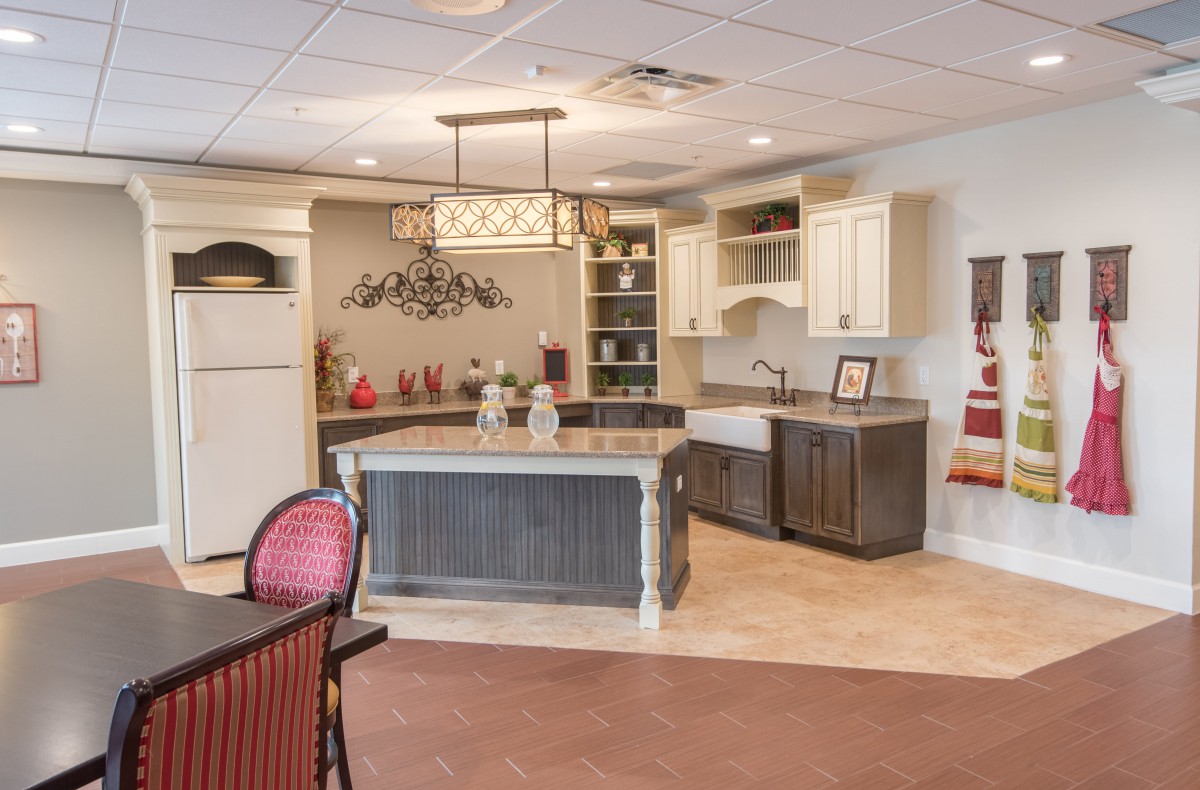 A modern kitchen interior featuring a central island with white cabinets and a farmhouse sink.