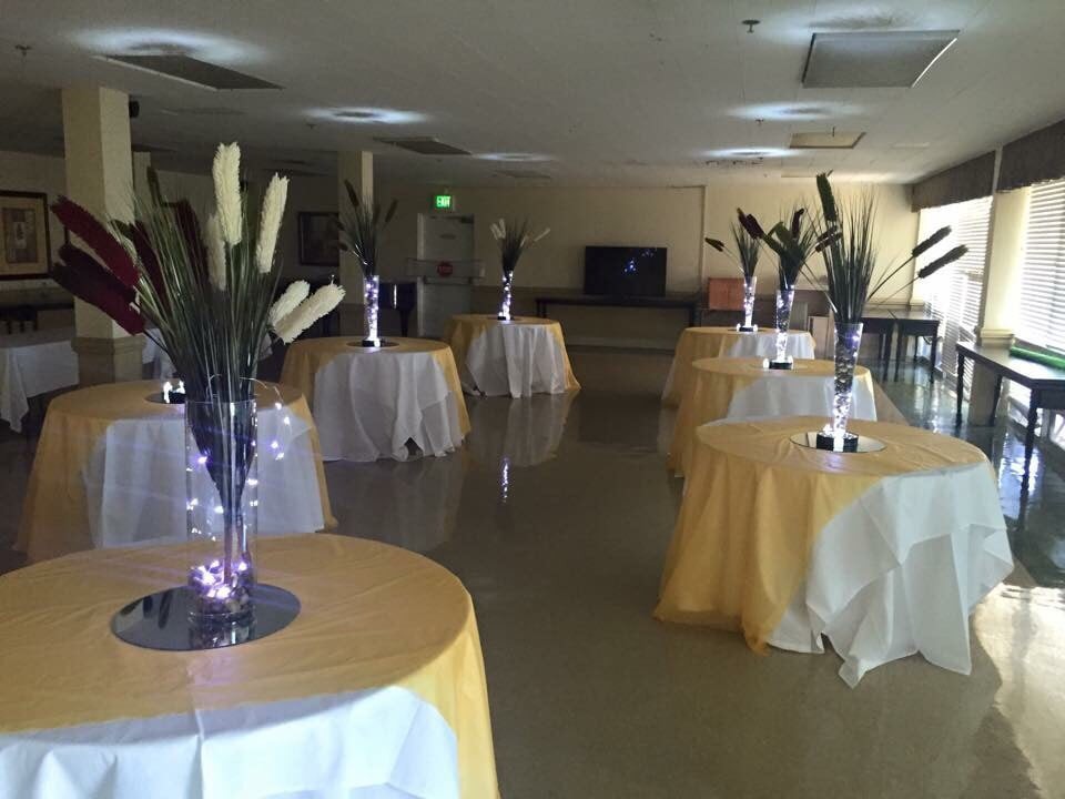 A formal event venue with decorated tables and elegant centerpieces.