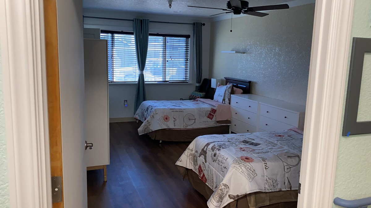 A tidy bedroom with two beds and a window letting in natural light.